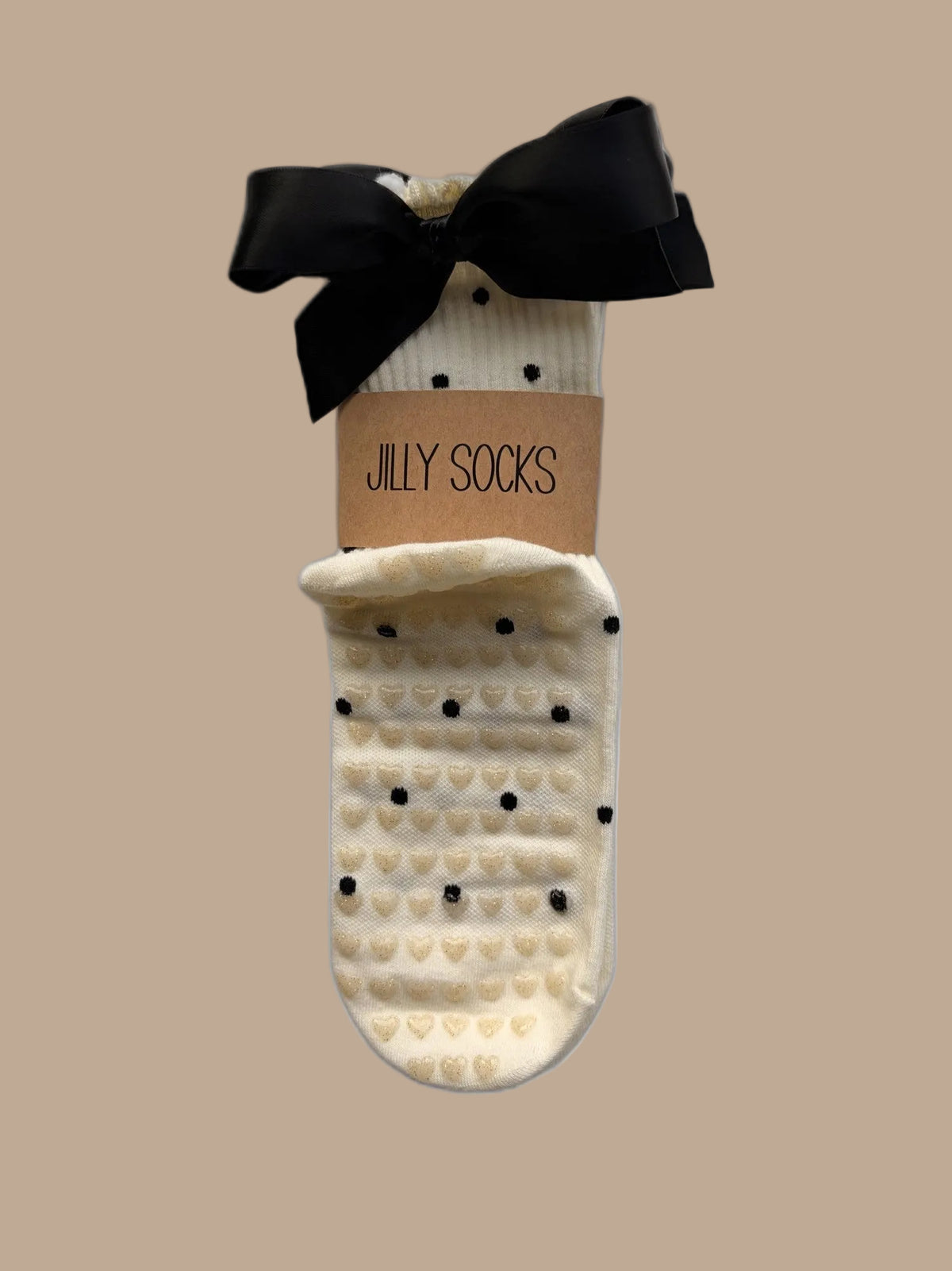Cute, fashionable black with off-white Pilates grip socks with a black satin bow and a tan paper band reading 'JILLY SOCKS' on a white background.