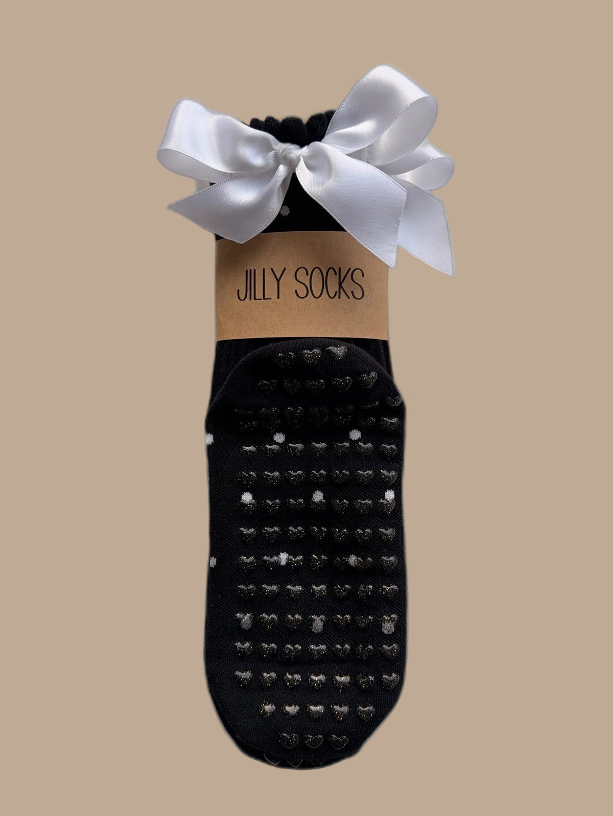 Cute, fashionable black with white polka dots Pilates grip sock with a white satin bow and a tan paper band reading 'JILLY SOCKS' on a white background.
