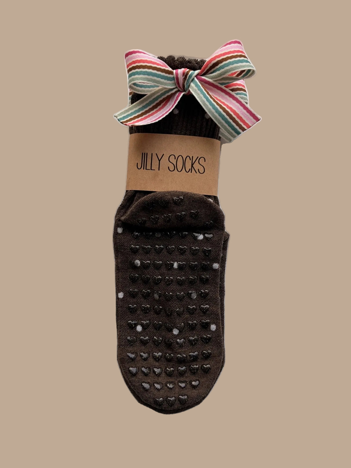 Cute, fashionable brown with off-white Pilates grip socks with a bright colors stripes bow and a tan paper band reading 'JILLY SOCKS' on a white background.